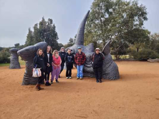 A group of participants and workers together at an outdoor sculpture park.