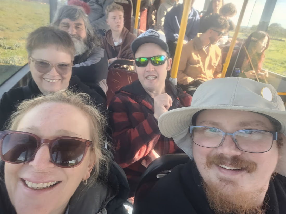 A group of participants and support workers on a day trip by bus.